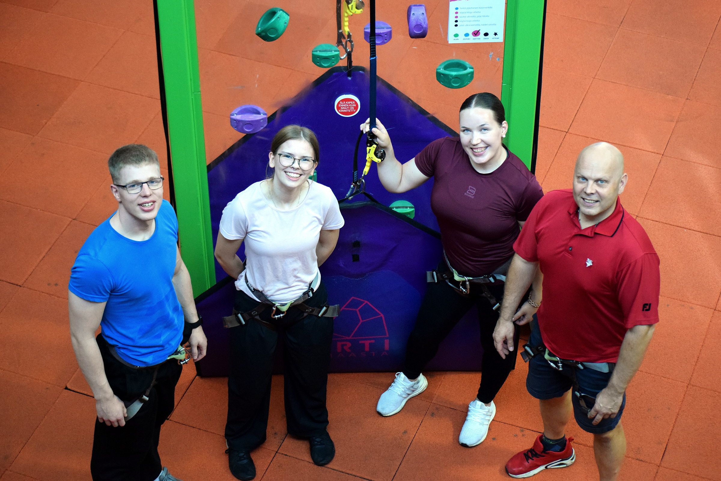 A group of climbers in harnesses by the wall